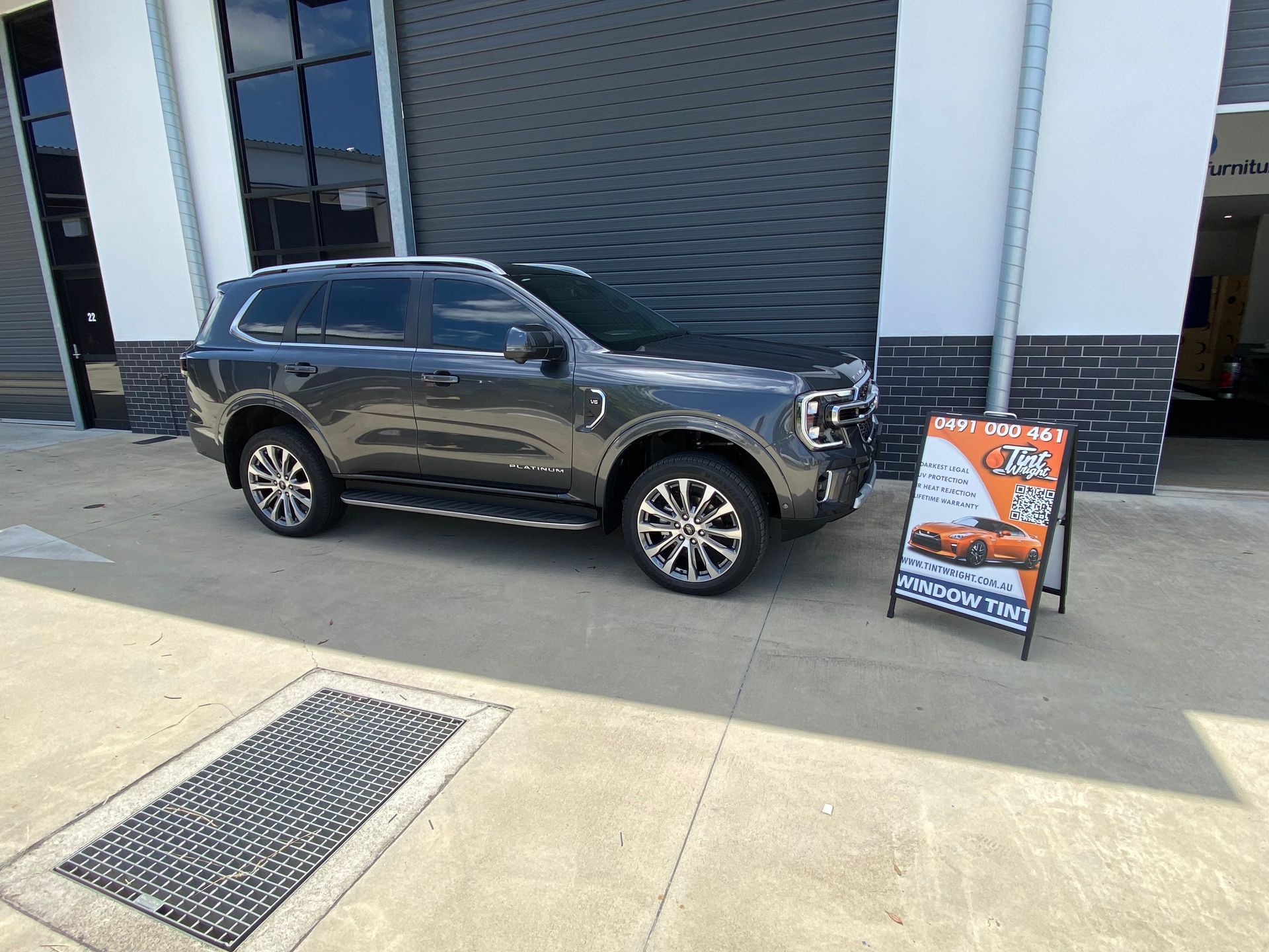 A black suv is parked in front of a building next to a sign.