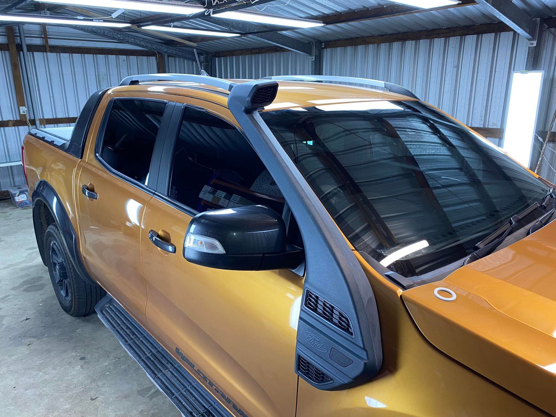 A pickup truck with a snorkel is parked in a garage.