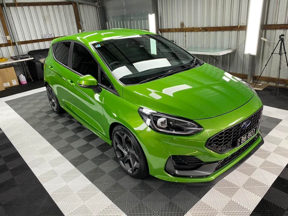 A green ford fiesta st is parked in a garage.