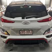 A white hyundai kona is parked in a garage.