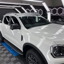 A white truck is parked on a lift in a garage - window tinting by Tint Wright Brisbane