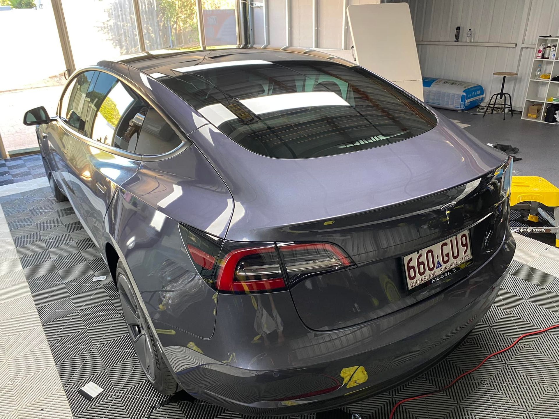 A tesla model 3 is parked in a garage.