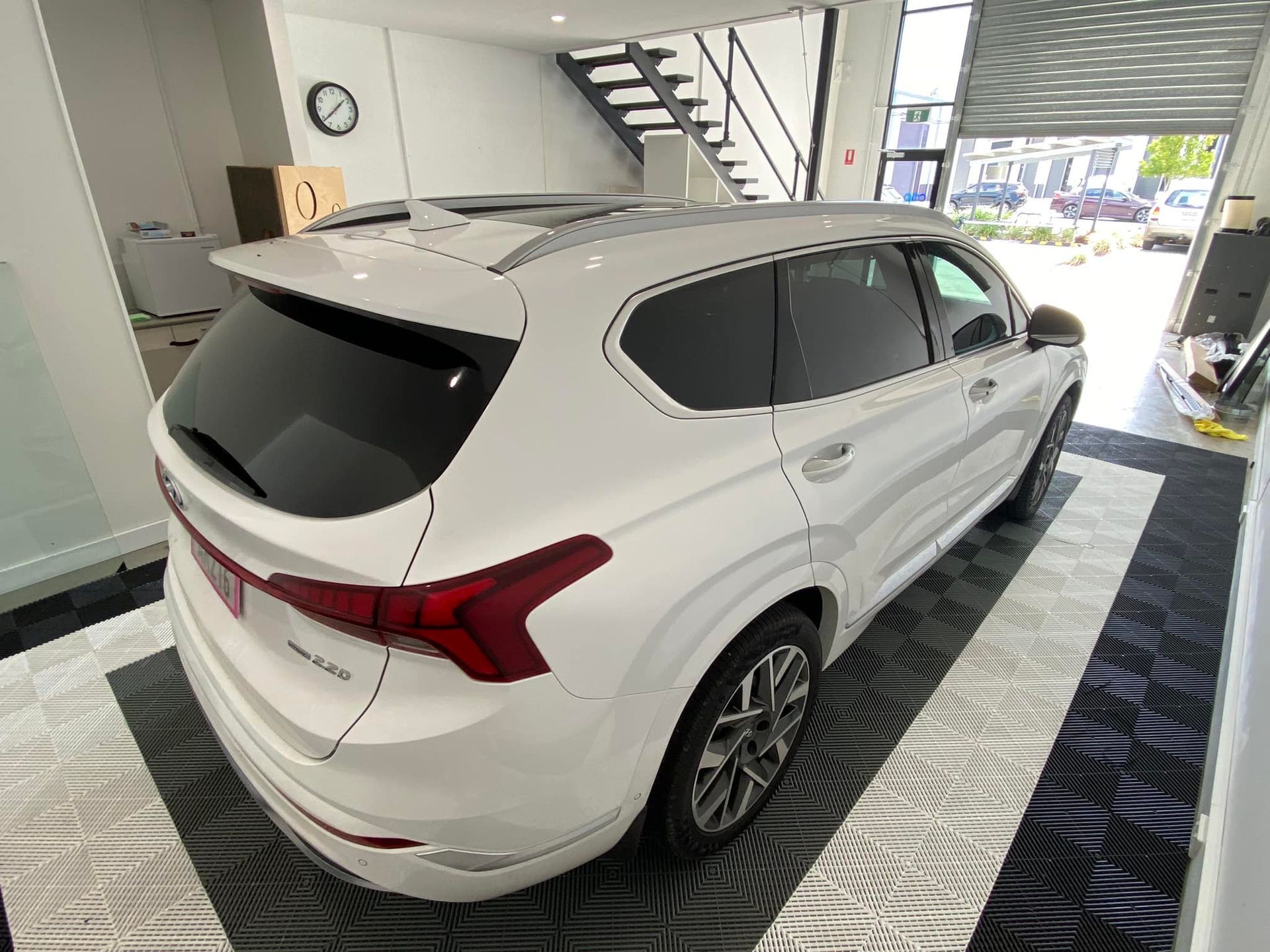 A white hyundai santa fe is parked in a garage.