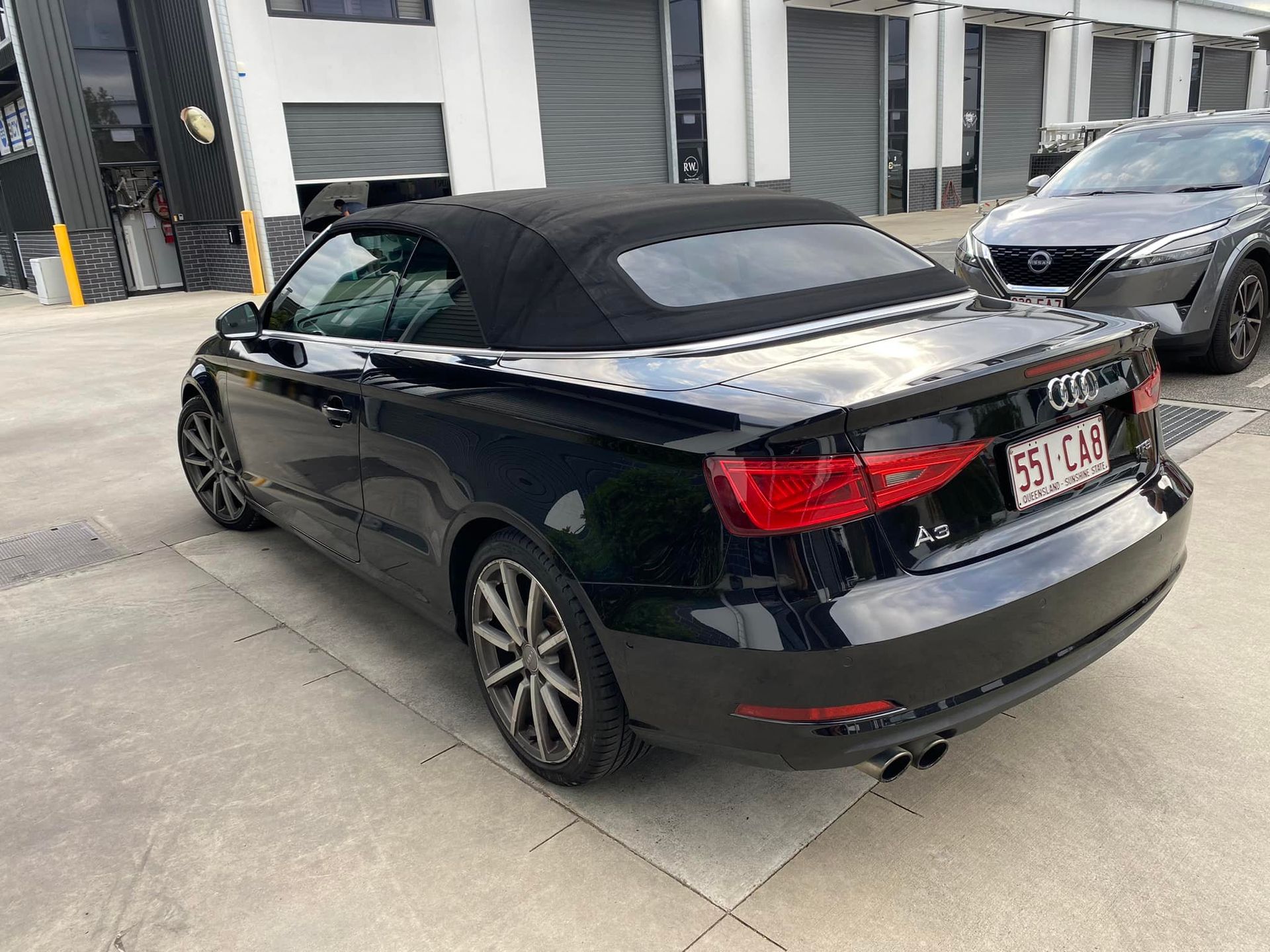 A black audi a3 convertible is parked in a parking lot.