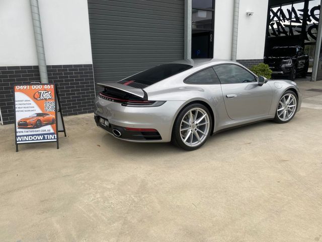 A silver porsche 911 is parked in front of a building - window tinting by Tint Wright Brisbane
