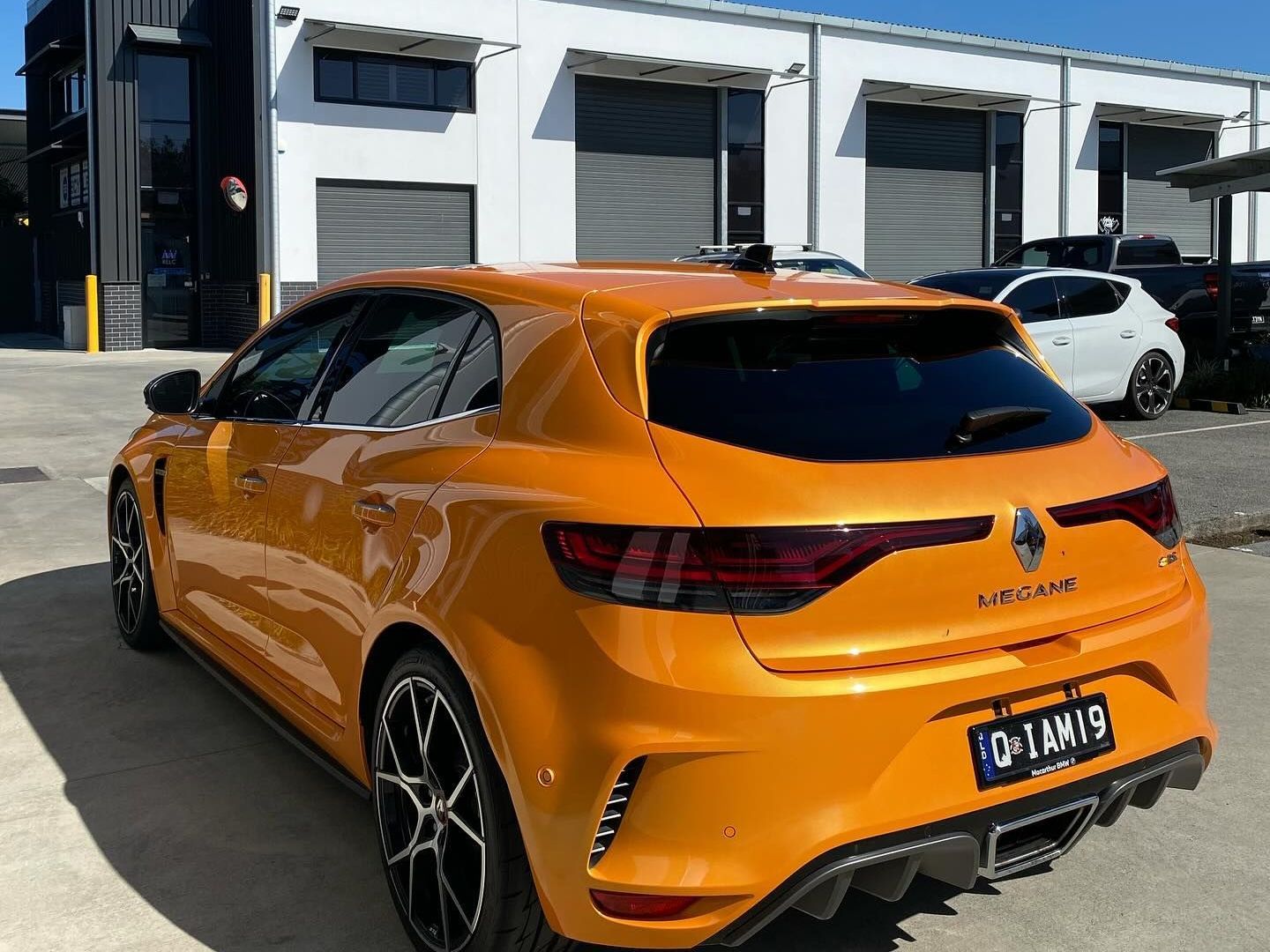 A renault megane rs hatchback is parked in front of a building.