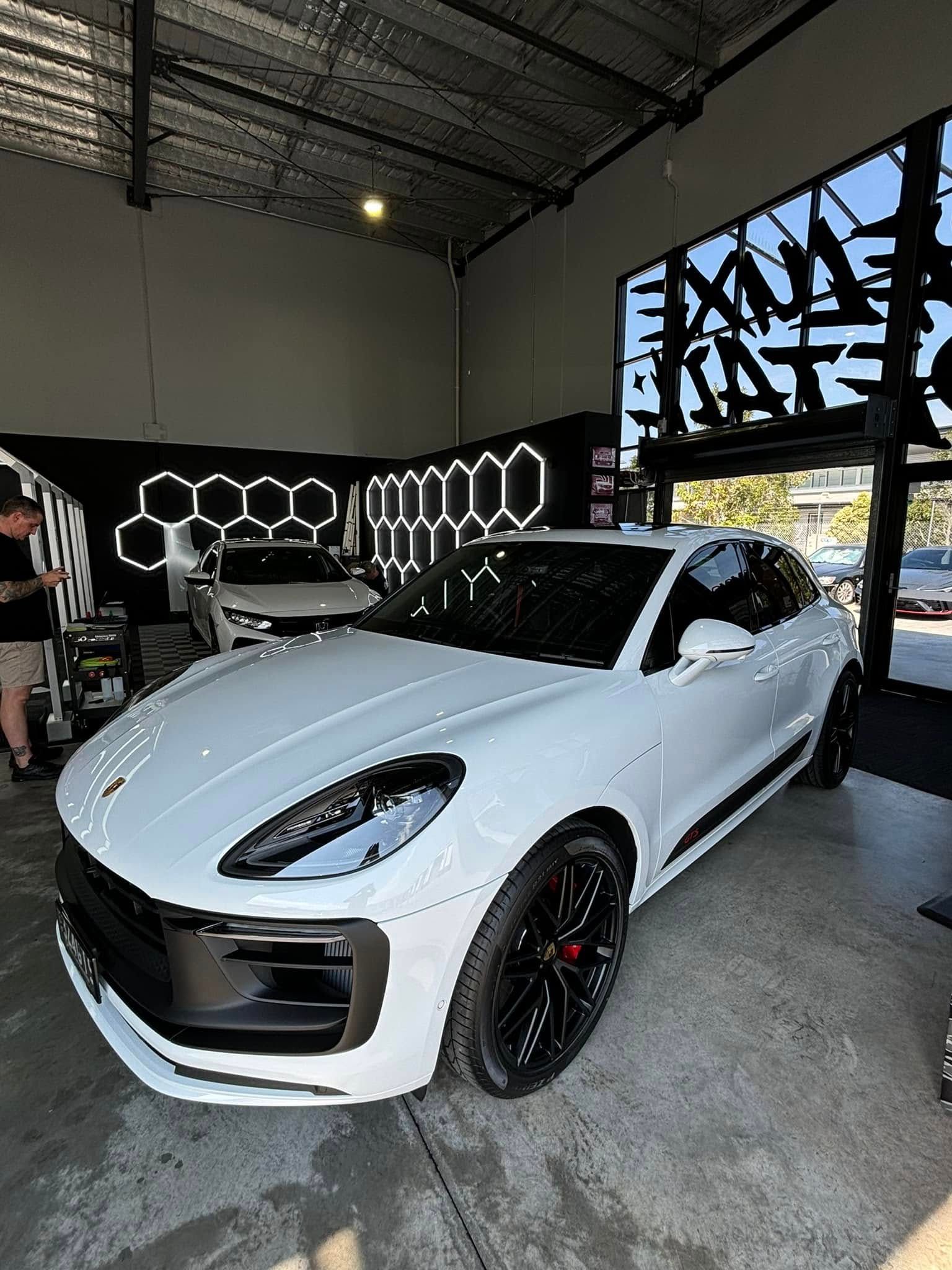 A white porsche macan turbo is parked in a garage.