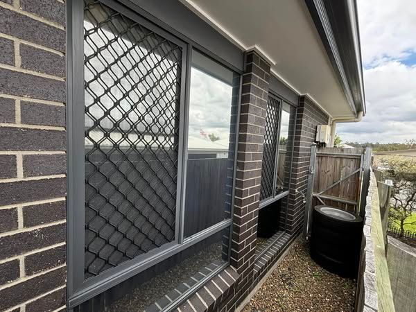 A brick building with a fence and a window - window tinting by Tint Wright Brisbane