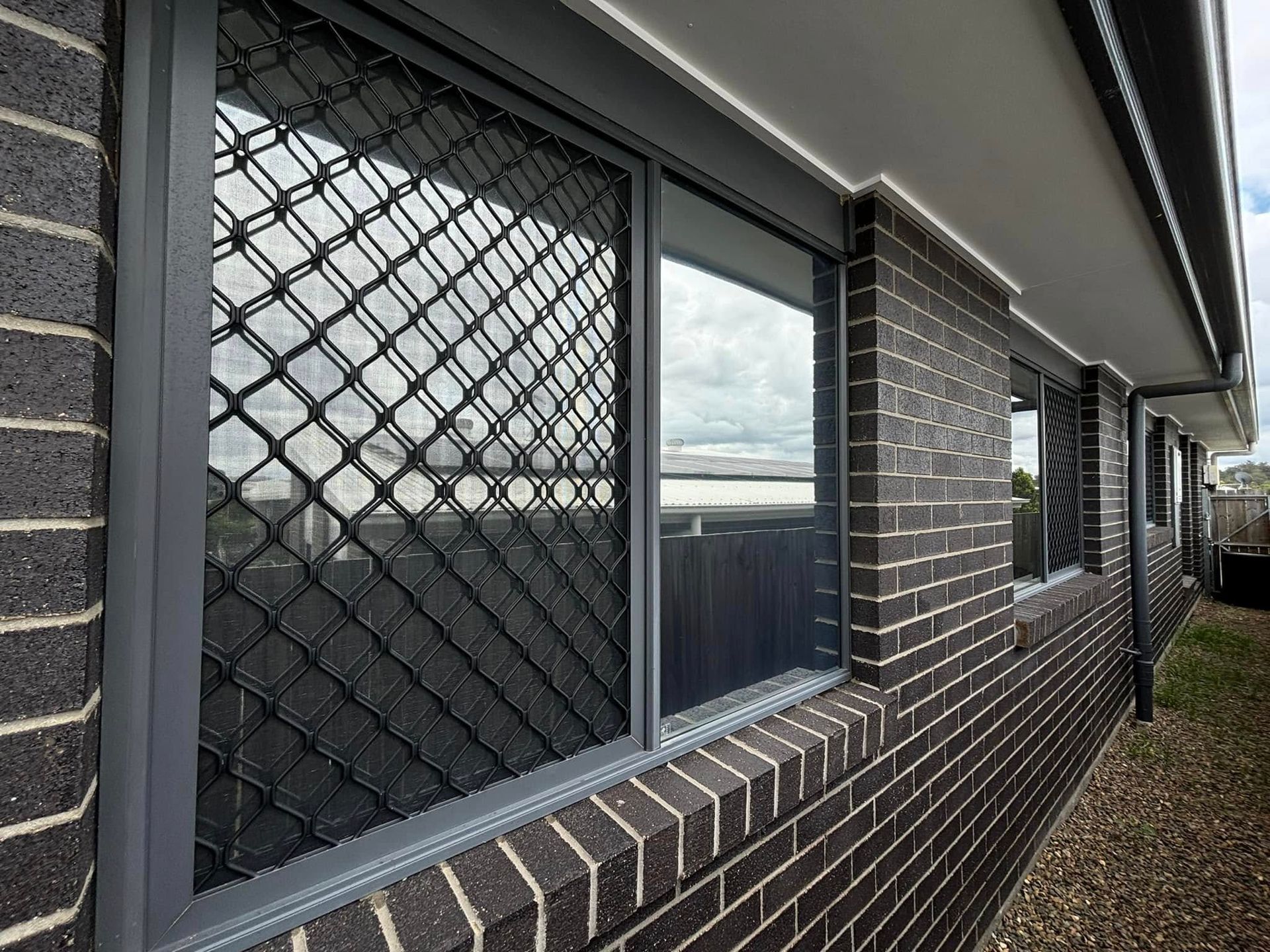 A brick building with a window with a chain link fence around it.