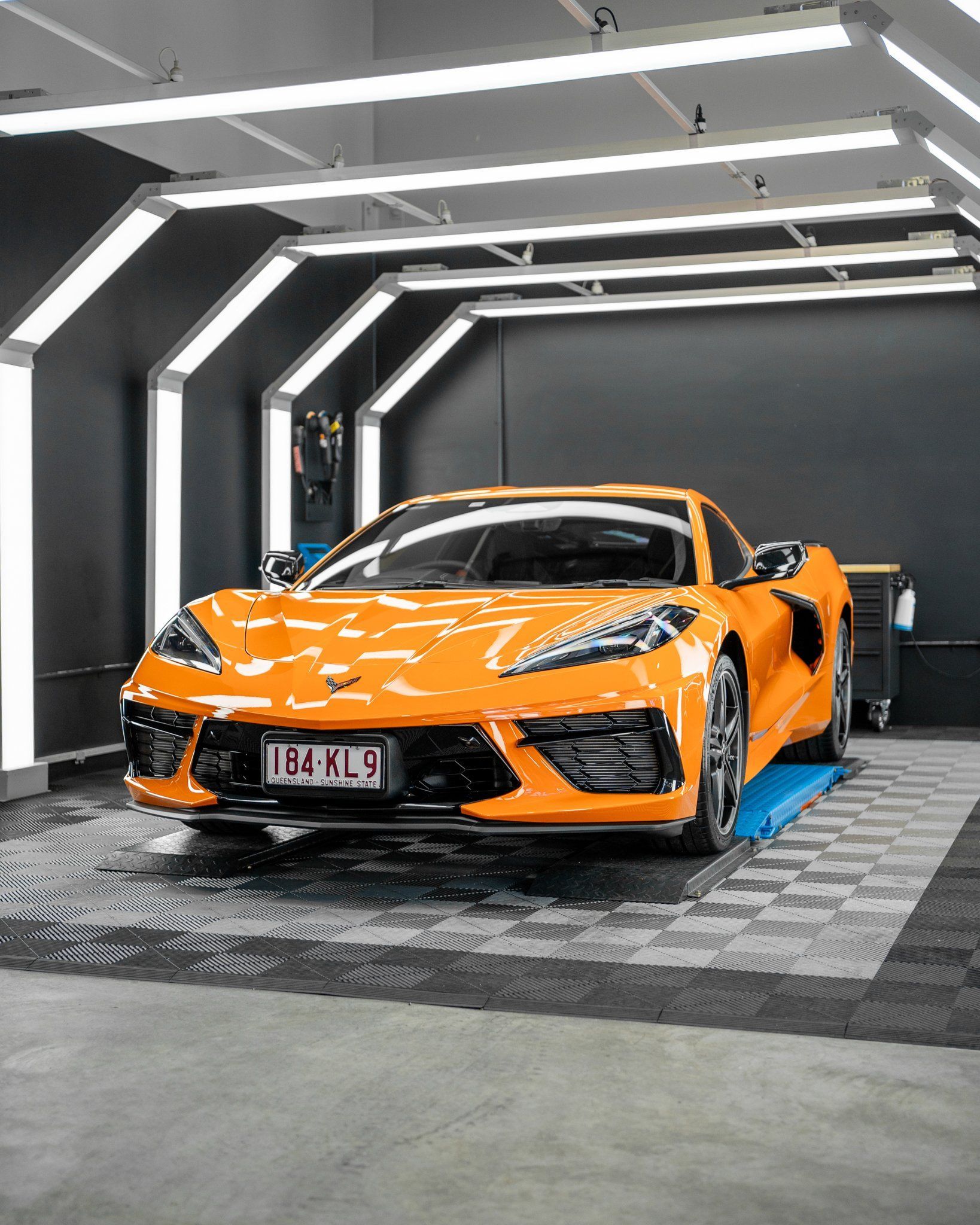 An orange sports car is parked in a garage.