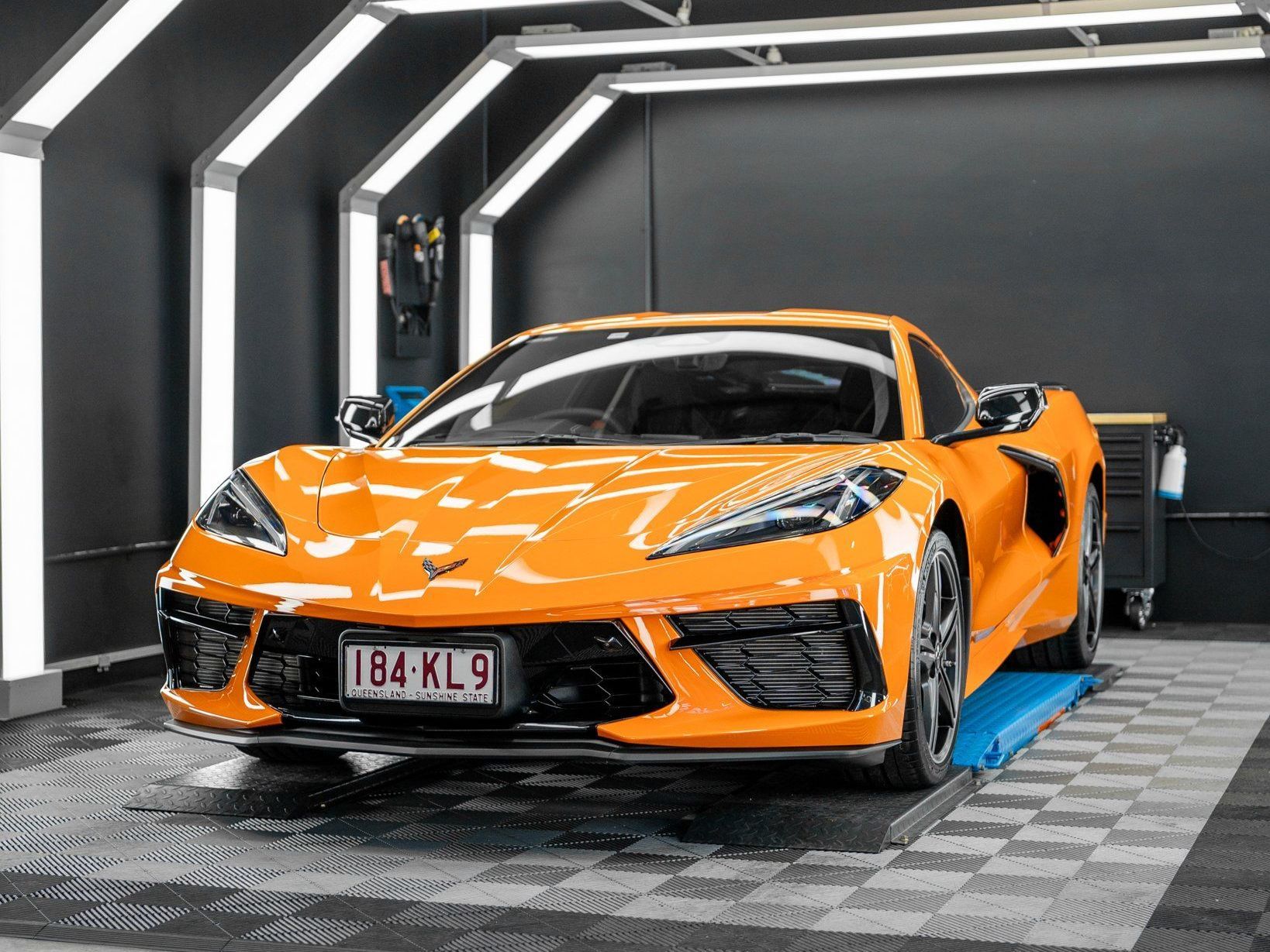 An orange sports car is parked in a garage.