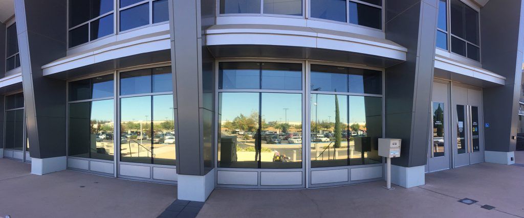 A large building with a lot of windows and a reflection of the sky in the windows.