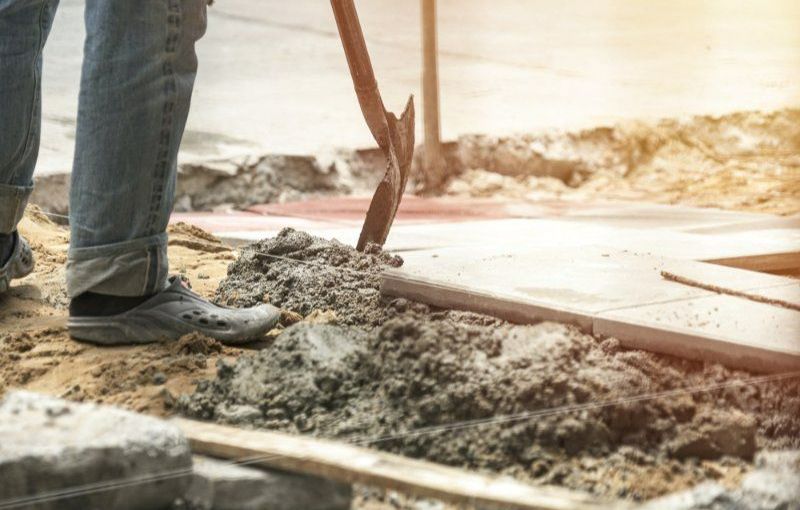 A Man is Digging in the Dirt With a Shovel — Turnscape Landscaping in Beechmont, QLD