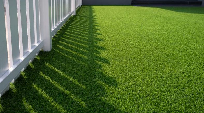 A White Fence is Surrounded by a Lush Green Lawn — Turnscape Landscaping In Broadbeach, QLD