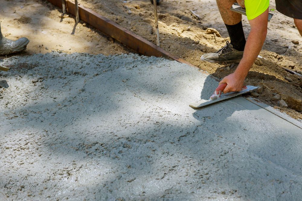 A man is using a trowel to spread concrete on a sidewalk. — Turnscape Landscaping in Hope Island, QLD