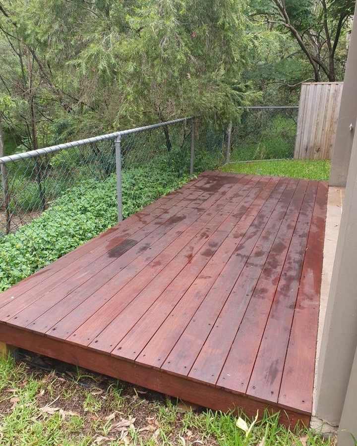 A wooden deck is sitting in the grass next to a fence. — Turnscape Landscaping in Hope Island, QLD