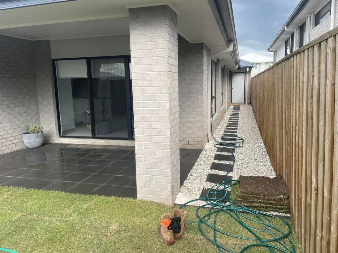 A hose is sitting on the grass in front of a house. — Turnscape Landscaping in Palm Beach, QLD