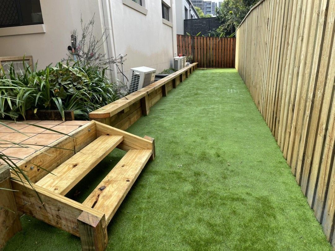 A wooden staircase leading up to a grassy area next to a wooden fence. — Turnscape Landscaping in Robina, QLD