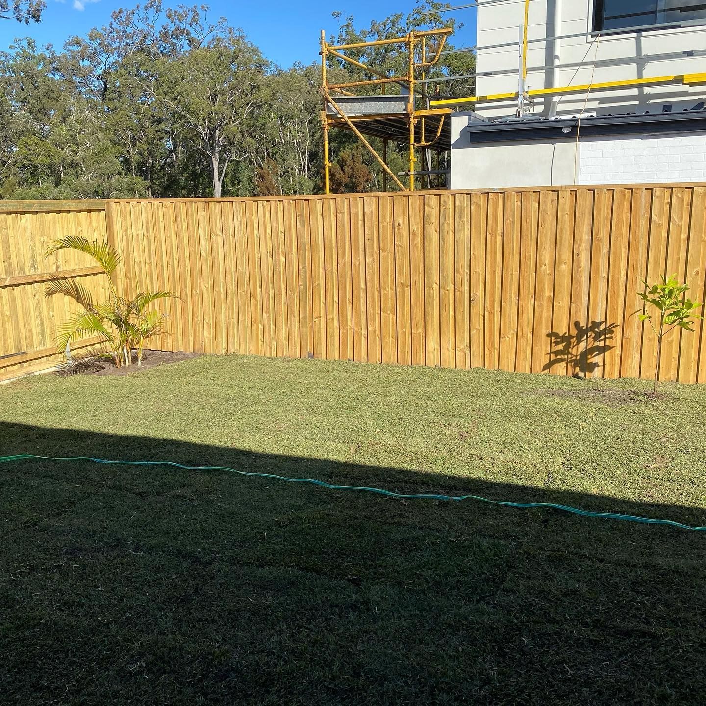 A wooden fence surrounds a lush green lawn in a backyard. — Turnscape Landscaping in Mudgeeraba, QLD