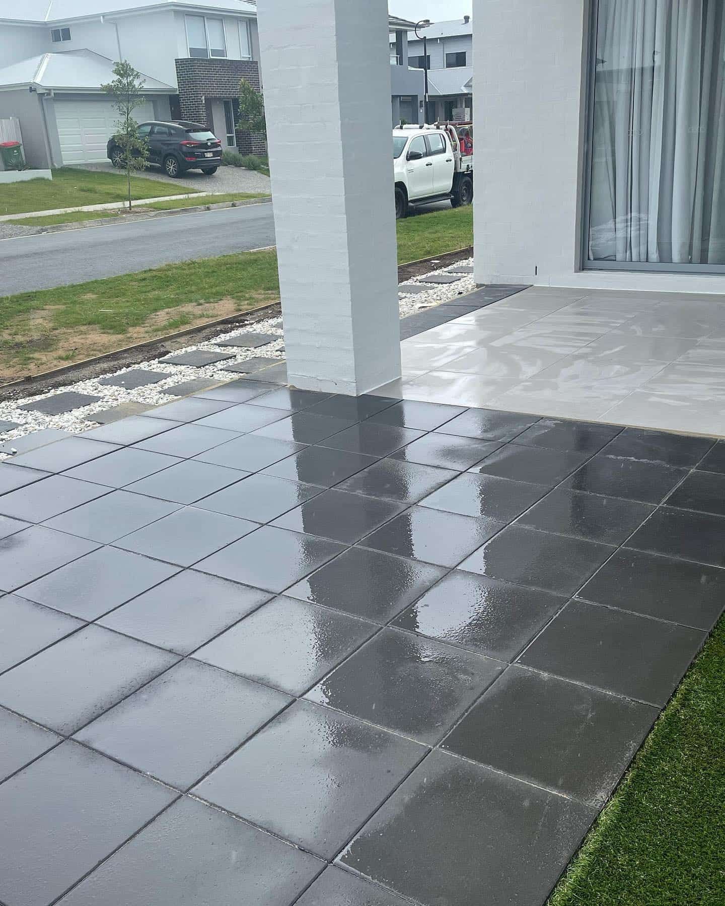 A patio with a car parked in the background and a reflection of a car in the tiles. — Turnscape Landscaping in Burleigh Heads, QLD