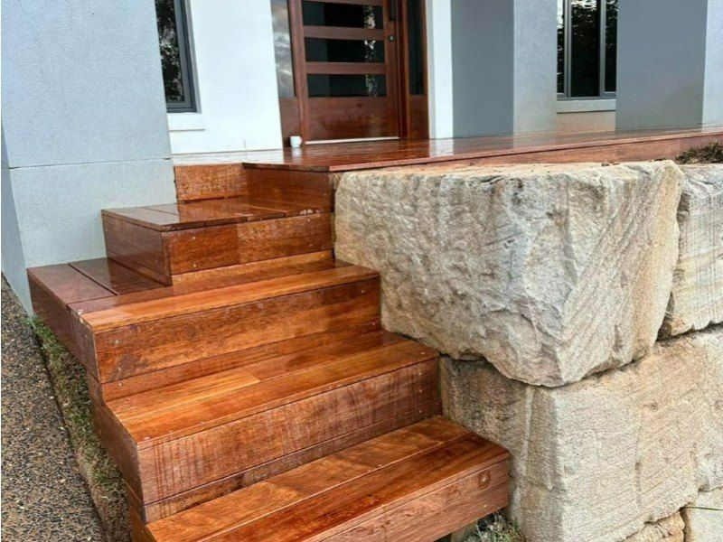 A Set of Wooden Stairs Leading Up to a Stone Wall — Turnscape Landscaping In Broadbeach, QLD