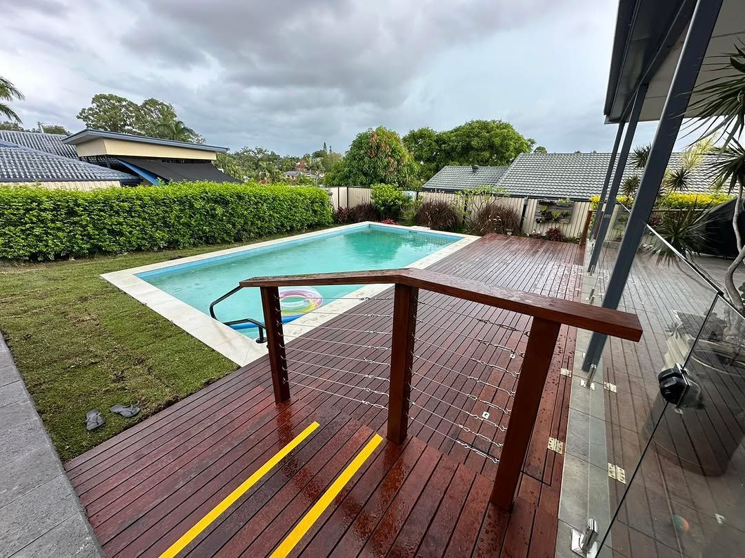 A wooden deck with stairs leading to a swimming pool. — Turnscape Landscaping In Broadbeach, QLD