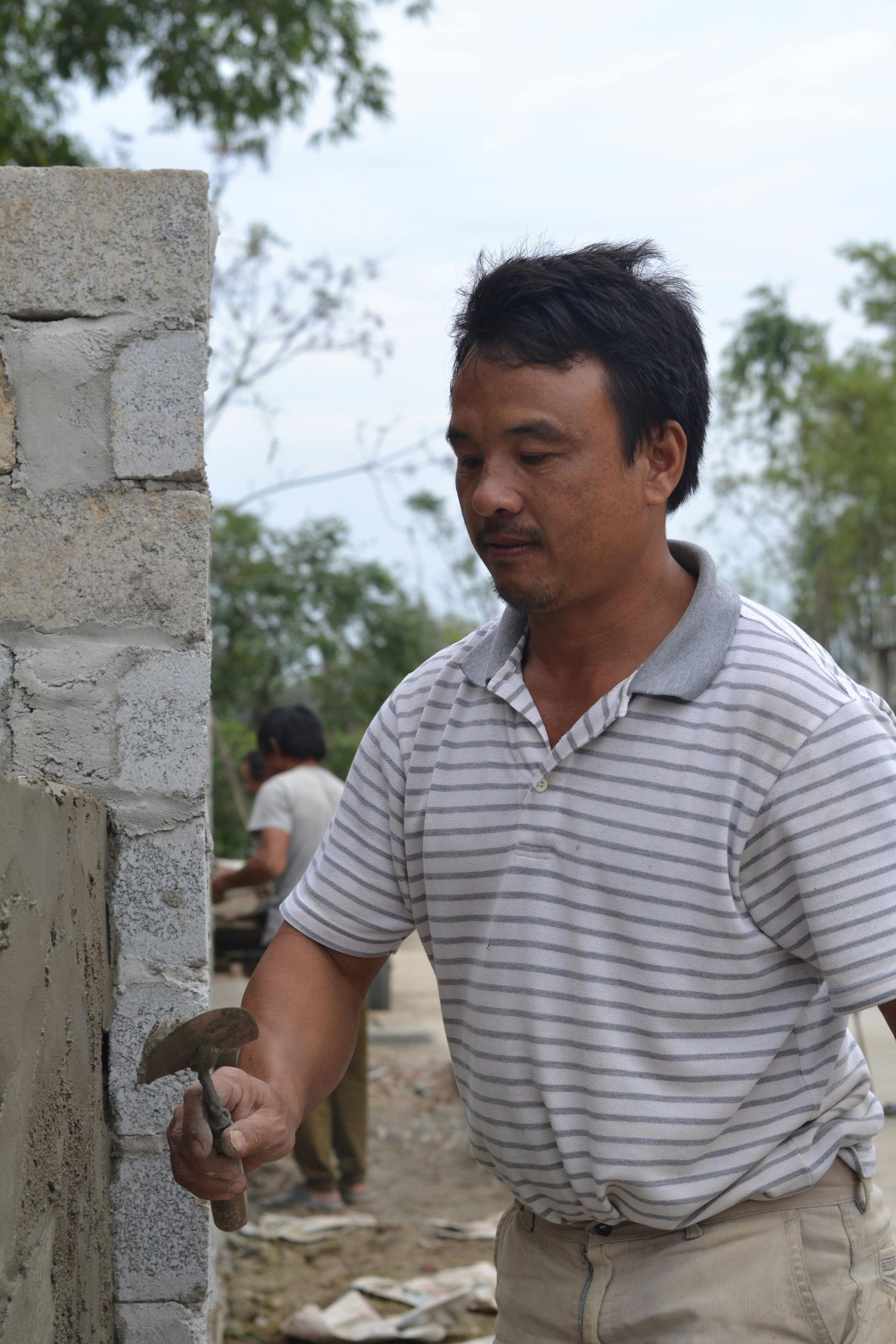 A man is working on a brick wall with a trowel.