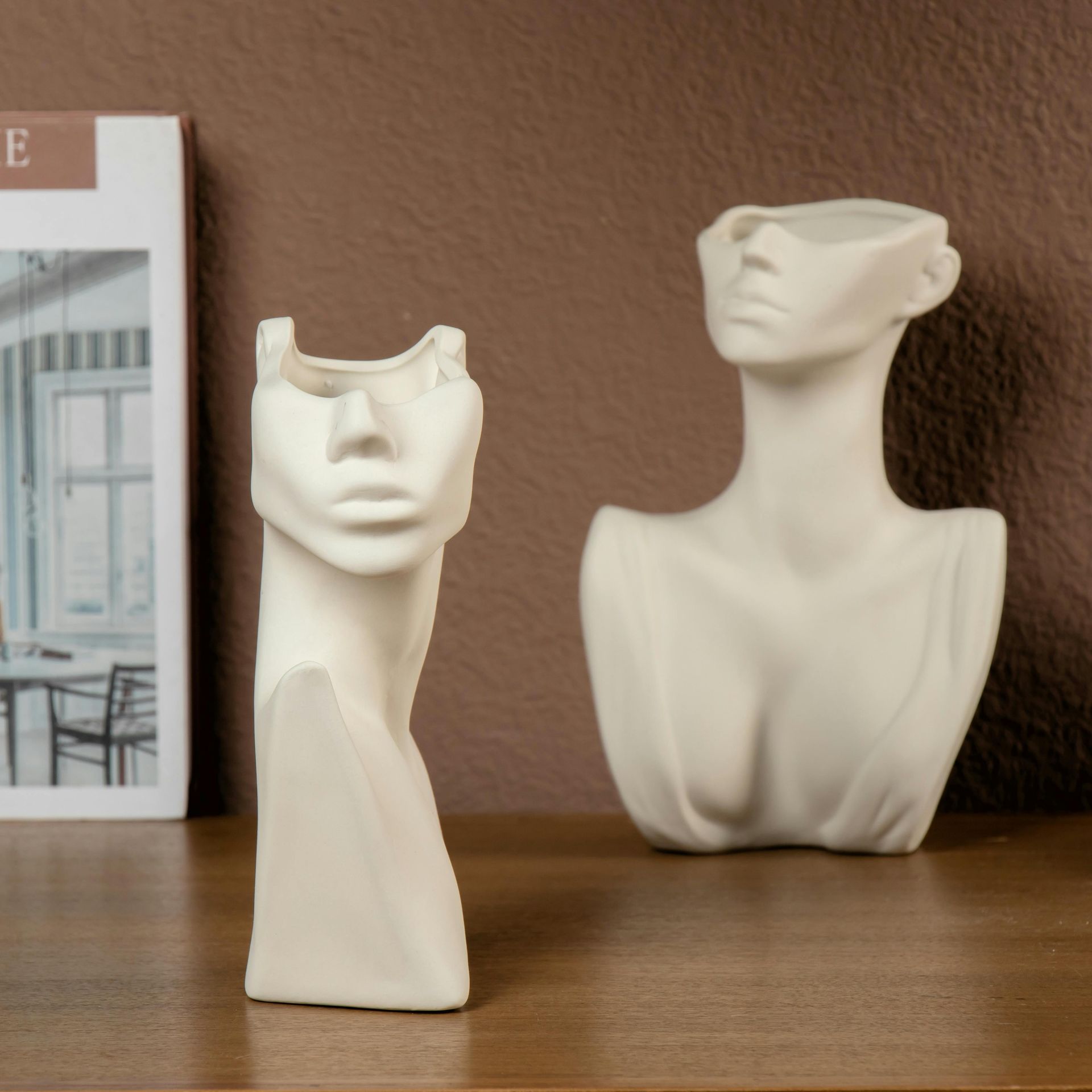 Two white vases with faces on them are on a table