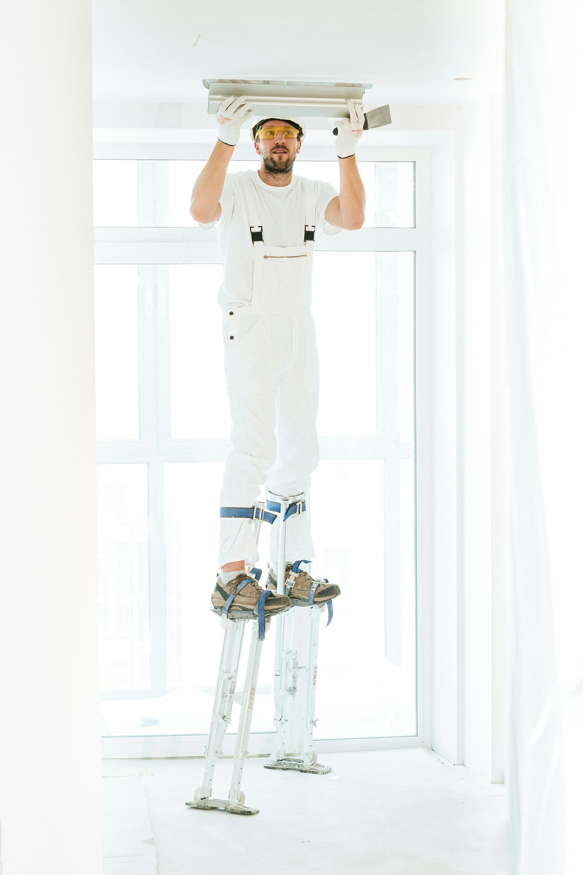 A man is standing on a ladder hanging a light fixture from the ceiling.