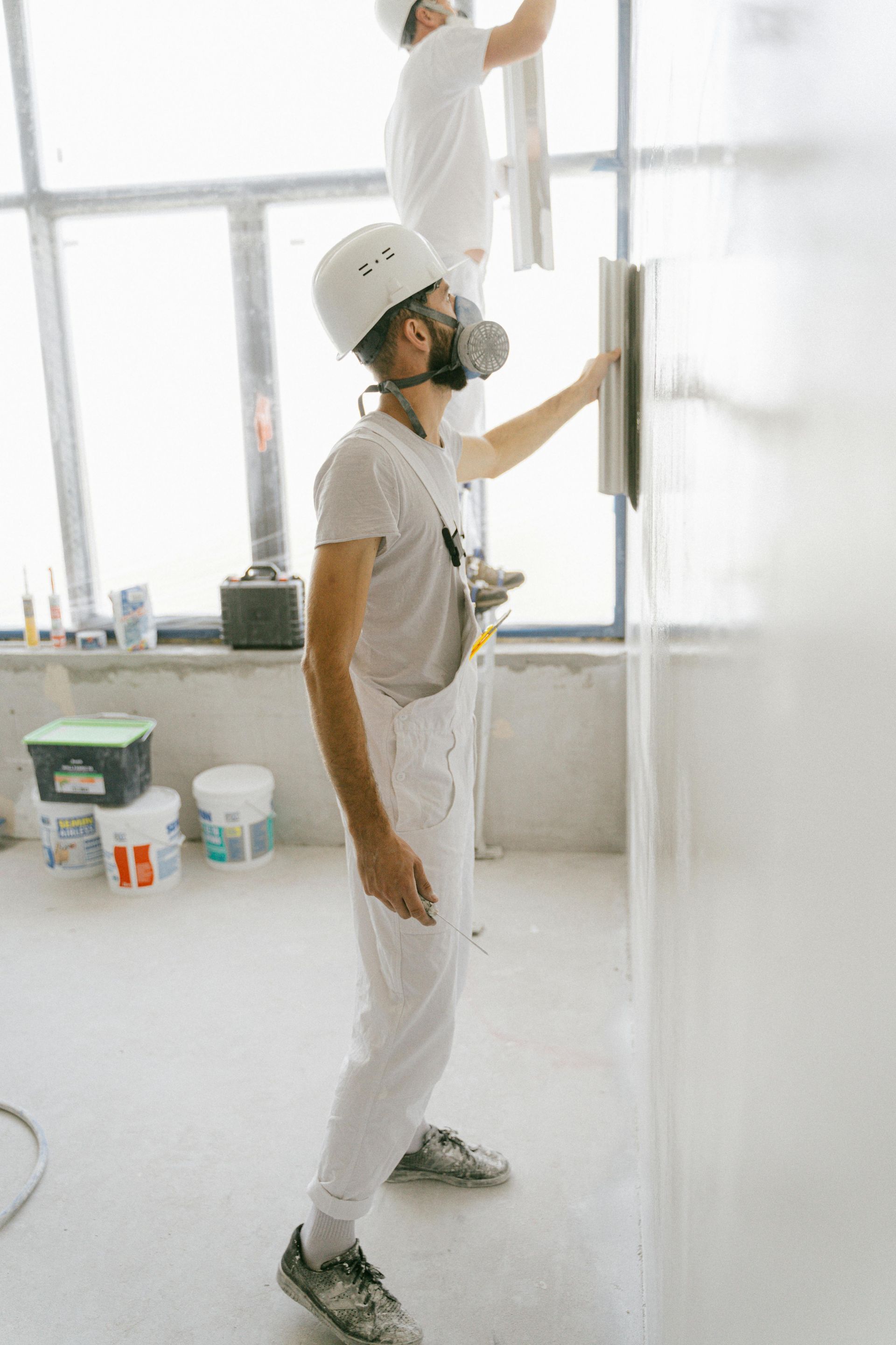 Two men are plastering a wall in a room.