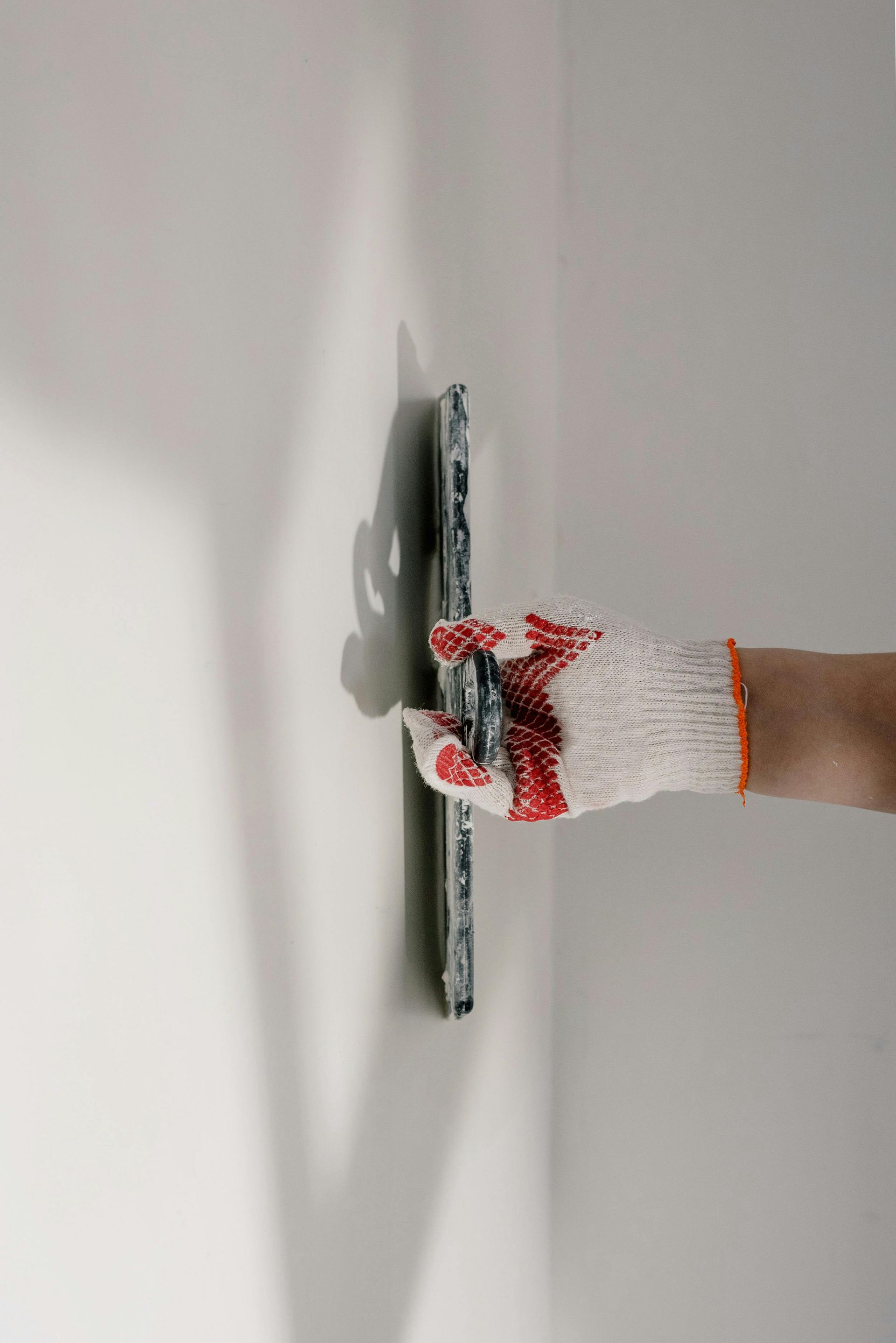 A person is plastering a wall with a trowel.