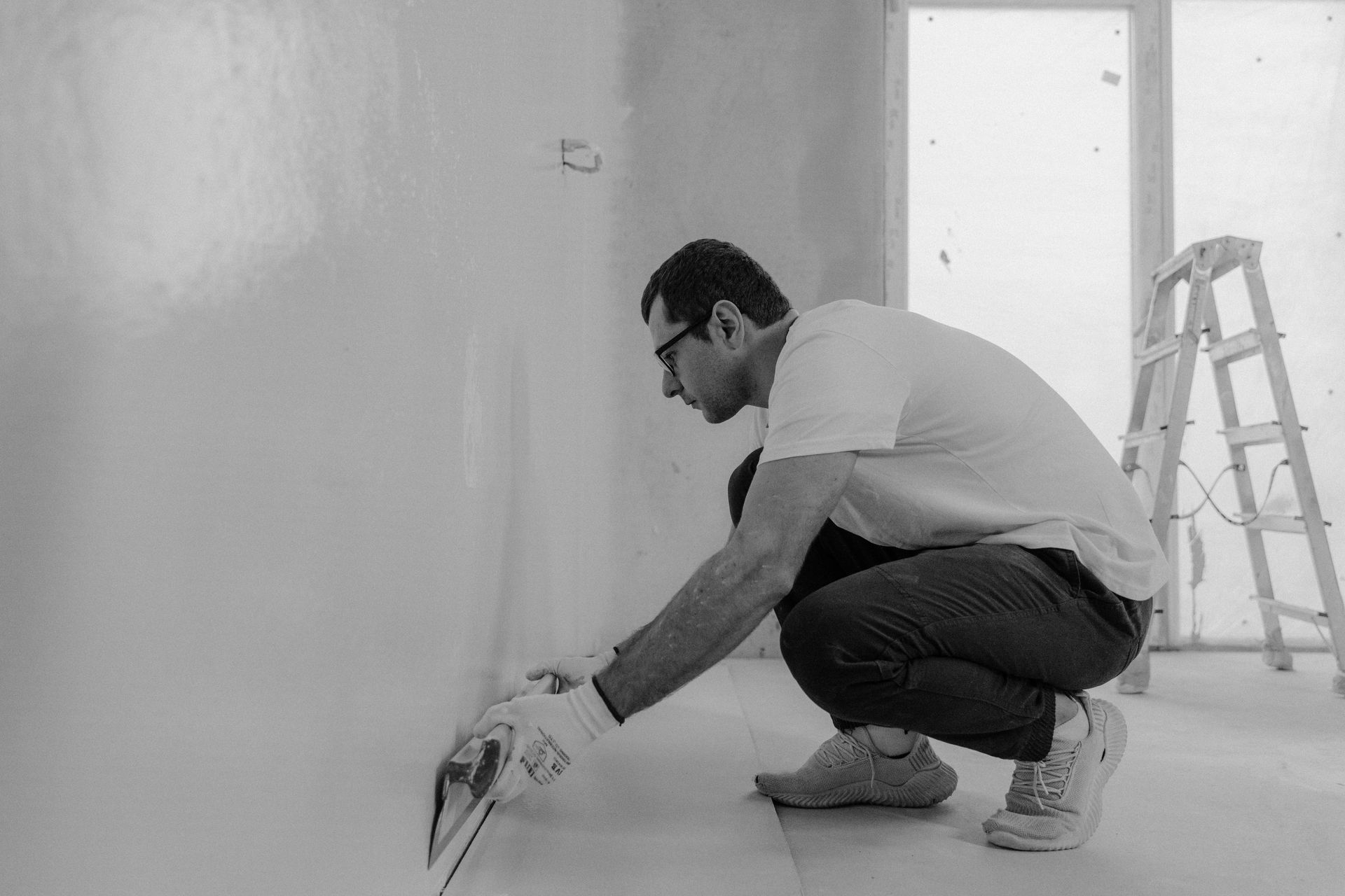 A man is plastering a wall in a black and white photo.