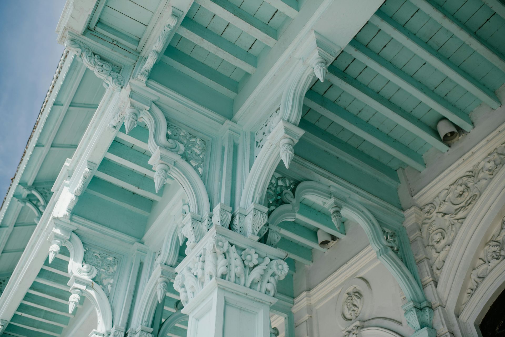 A close up of the ceiling of a building with a blue sky in the background.