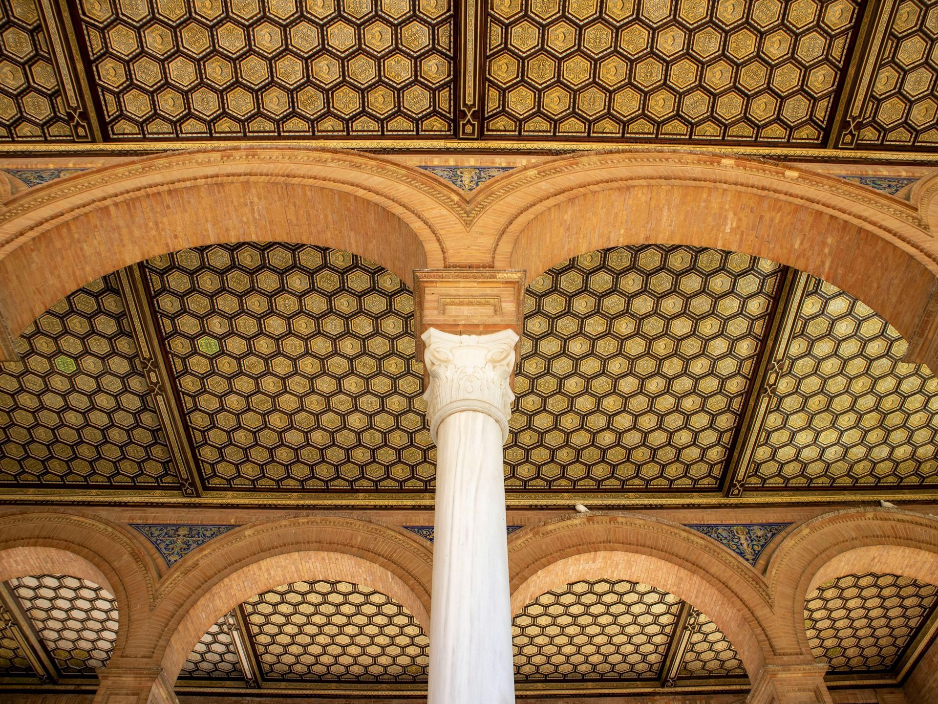 Looking up at the ceiling of a building with a pillar in the middle.