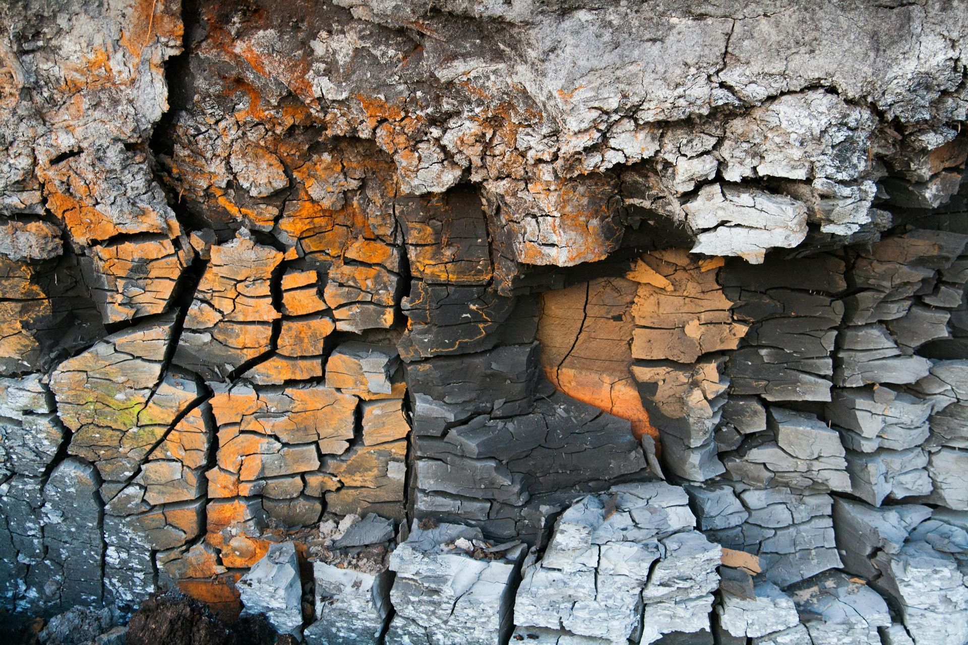 A close up of a cracked rock wall with a shadow on it.