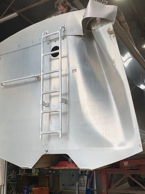A truck that has a curved back and a damaged tarp.