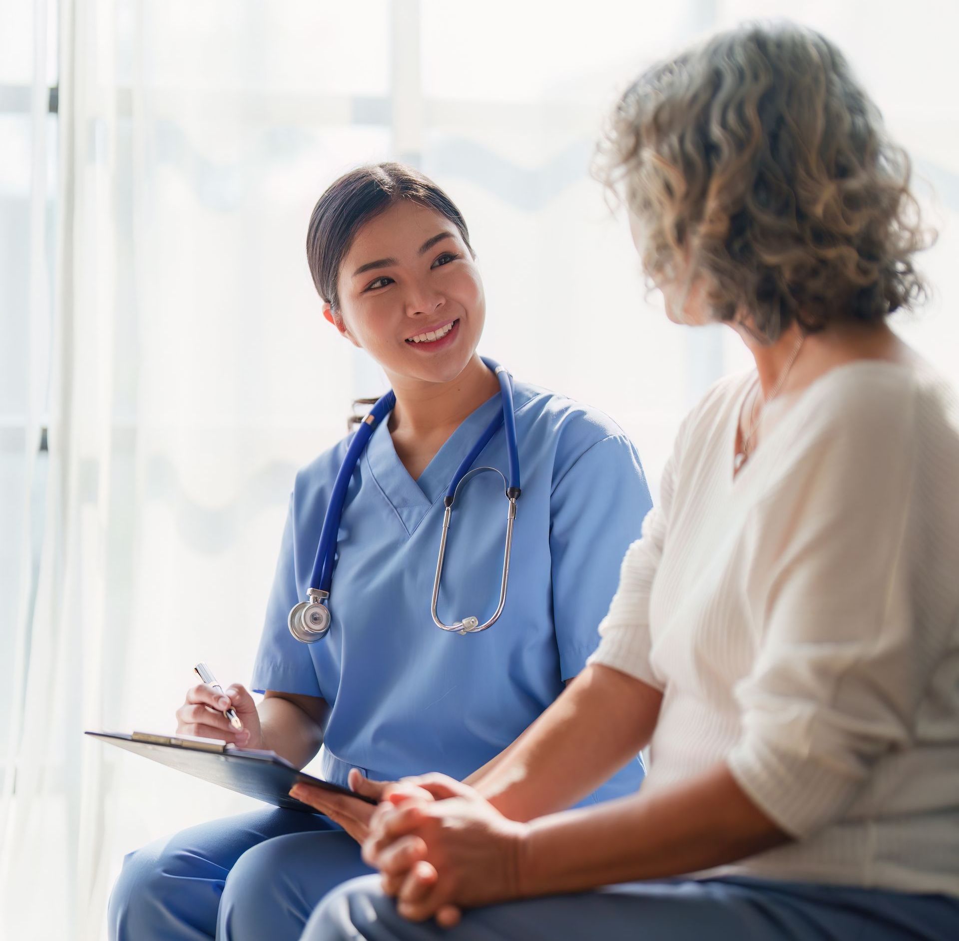 A man and a woman in scrubs are looking at a clipboard