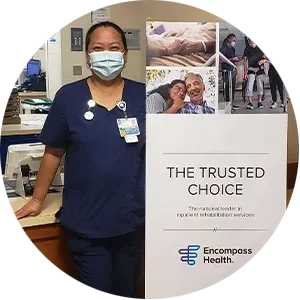 A nurse wearing a mask is standing next to a sign that says the trusted choice.