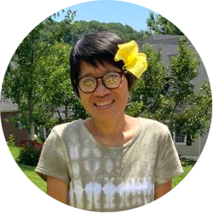 A woman wearing glasses and a yellow flower in her hair.