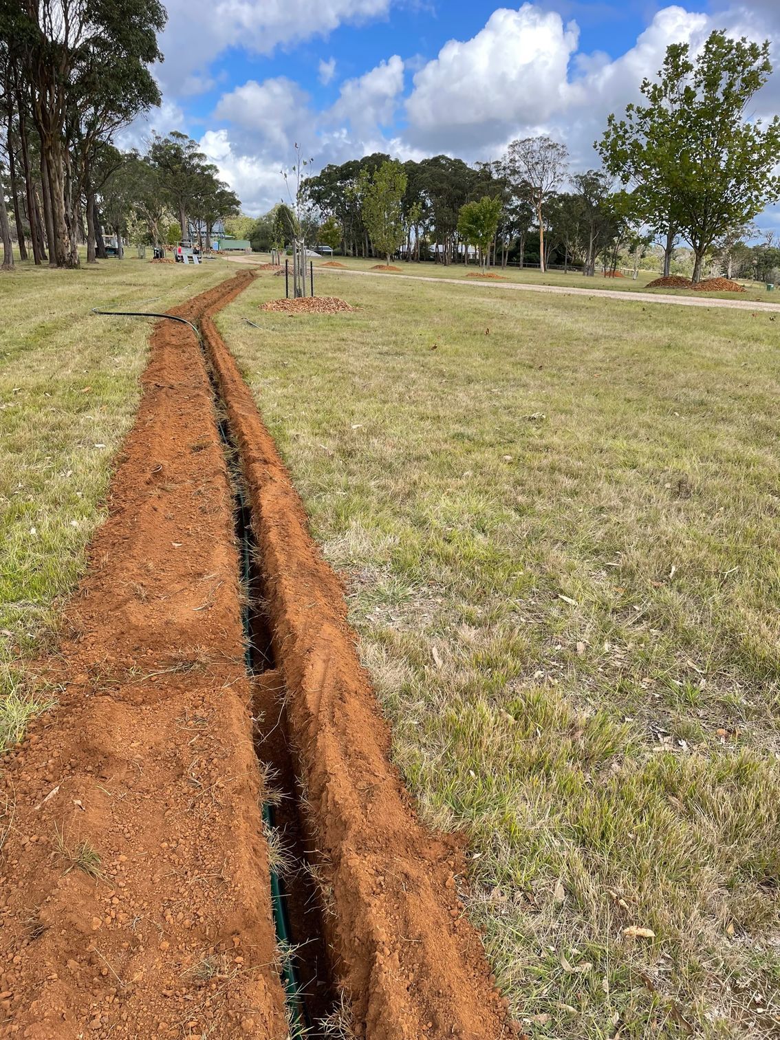 A dirt path going through a grassy field with trees in the background- Irrigation Solutions in Southern Highlands, NSW