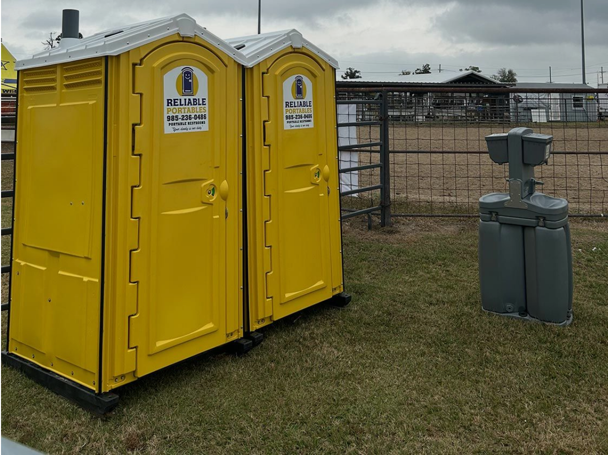 Two yellow portable toilets are sitting next to each other in a grassy field.