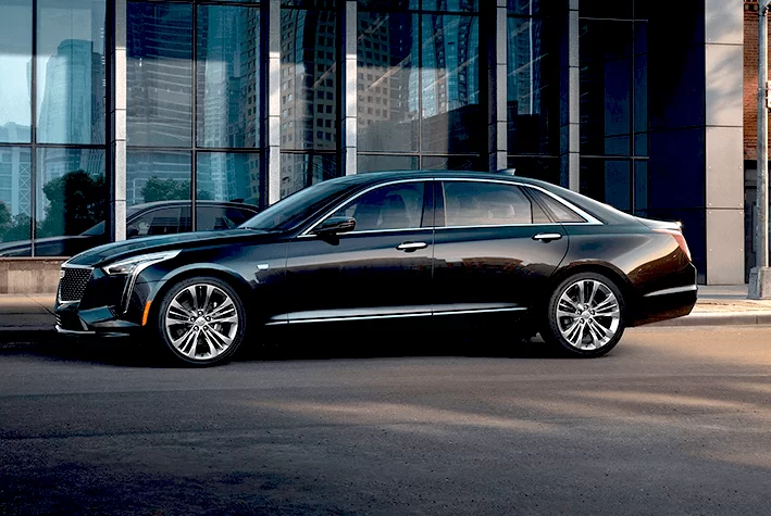 A black cadillac is parked in front of a building.