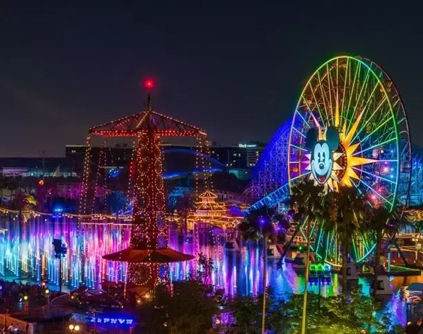 A ferris wheel is lit up at night in an amusement park.