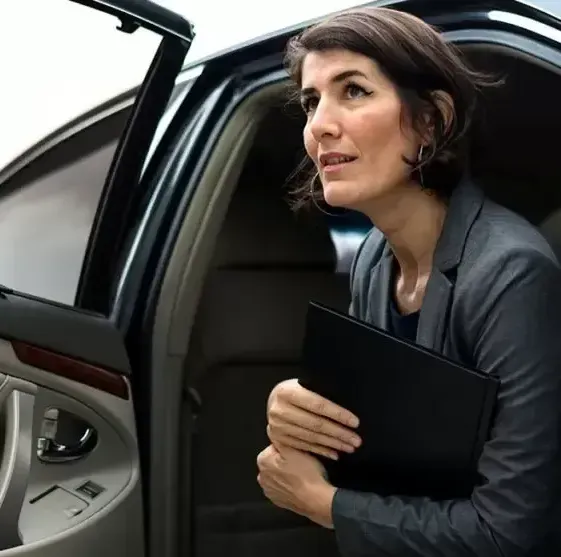 A woman in a suit is getting out of a car