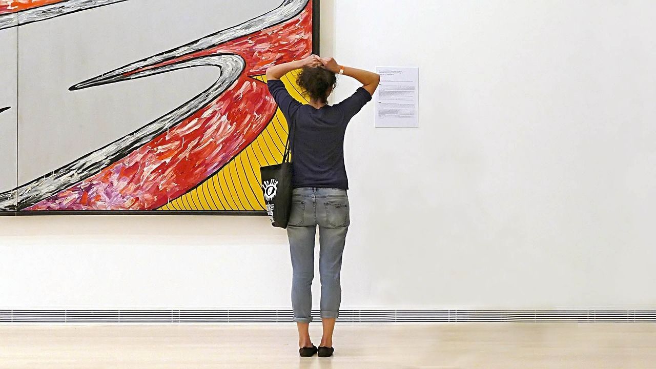 A woman is looking at a painting in a museum.