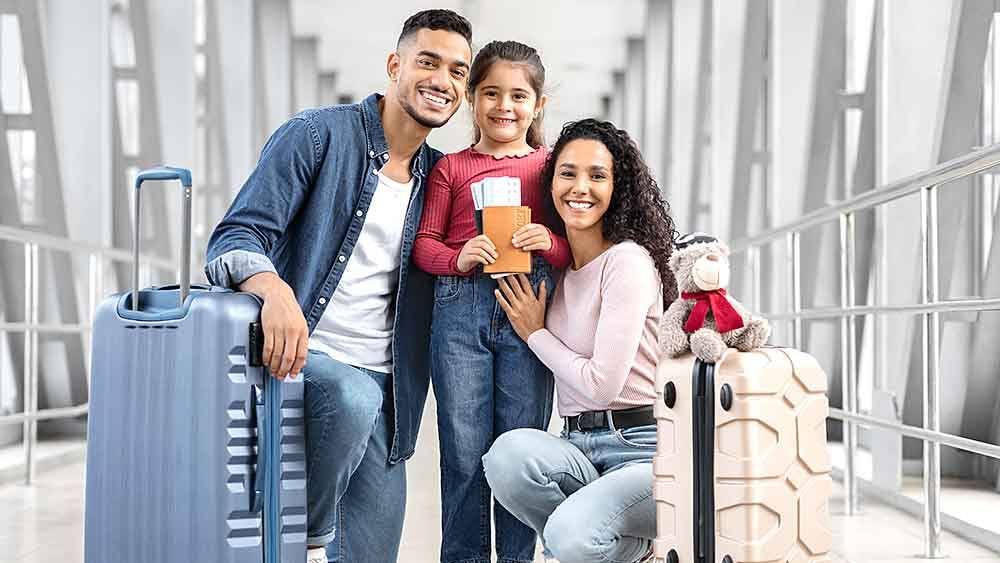 A family is posing for a picture in an airport with luggage.