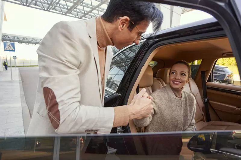 A man is helping a woman get out of a car.