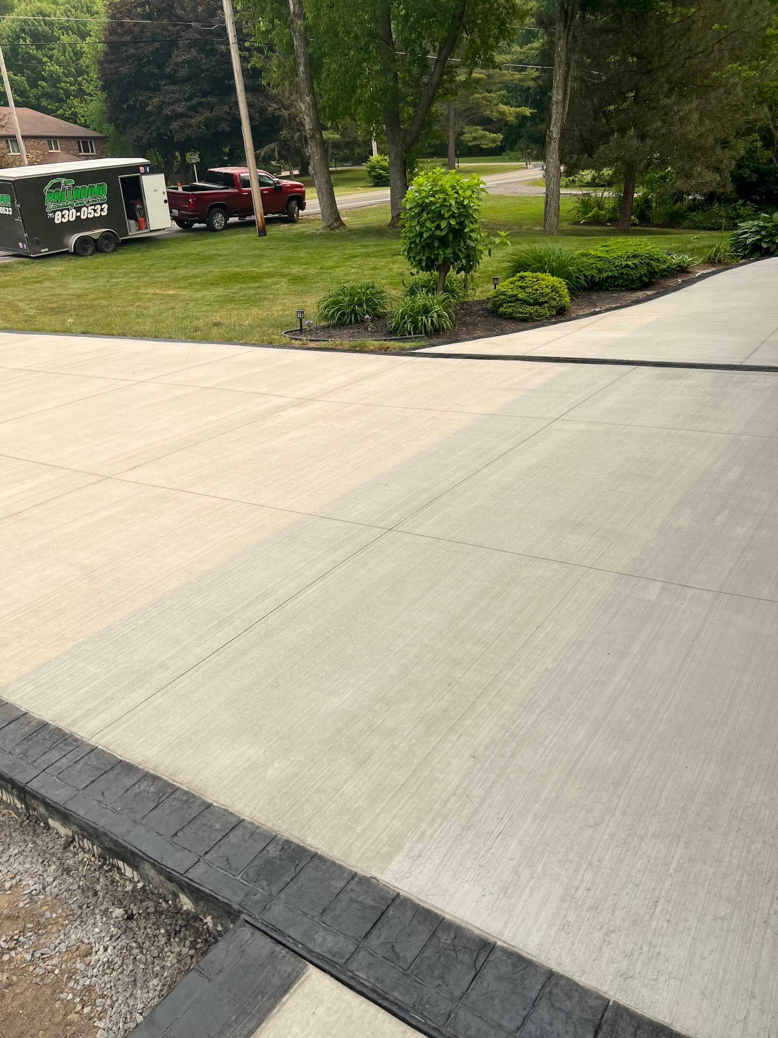A concrete driveway with a newly paved section; a green portable toilet is in the background.