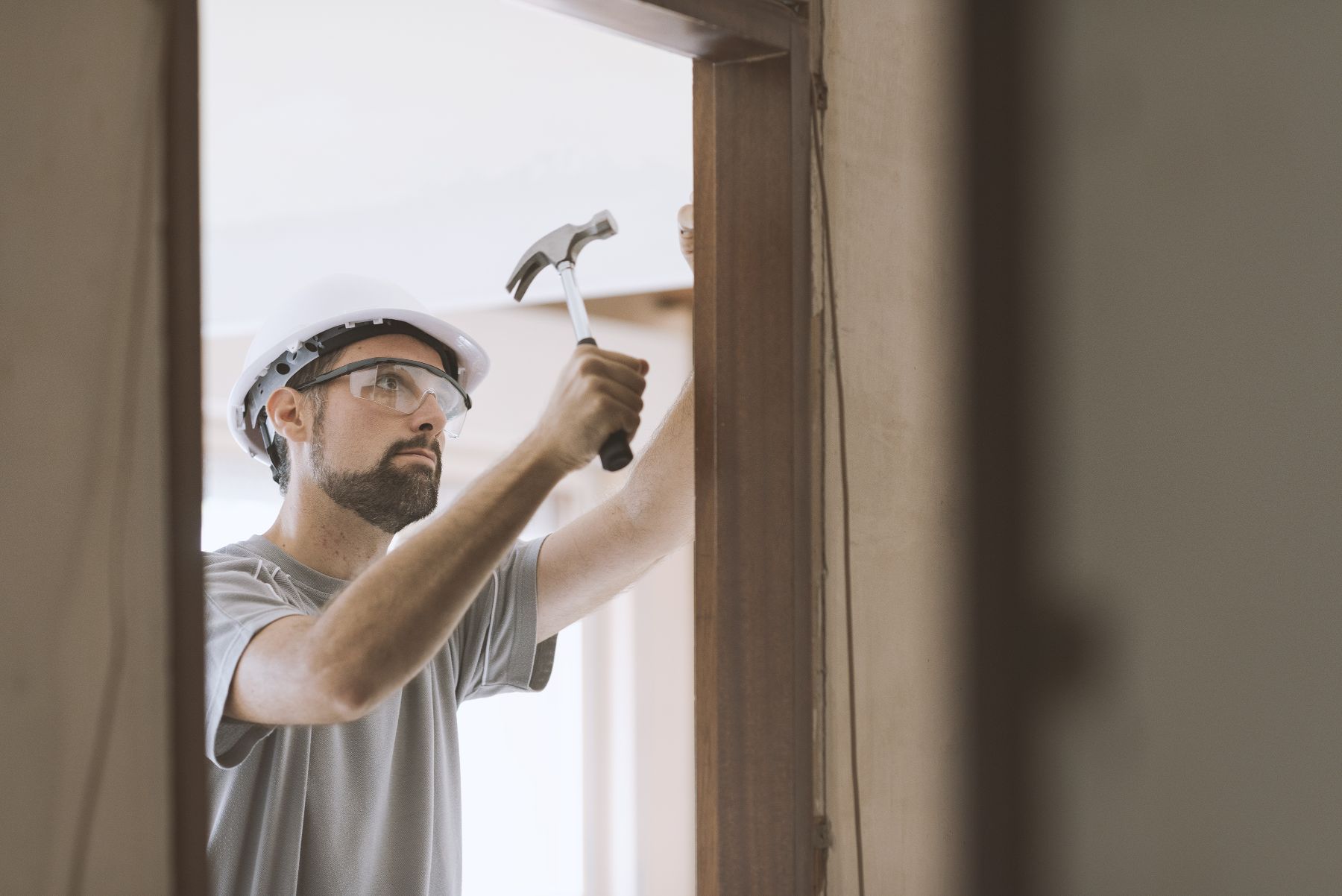 A man is using a hammer to fix a door frame.