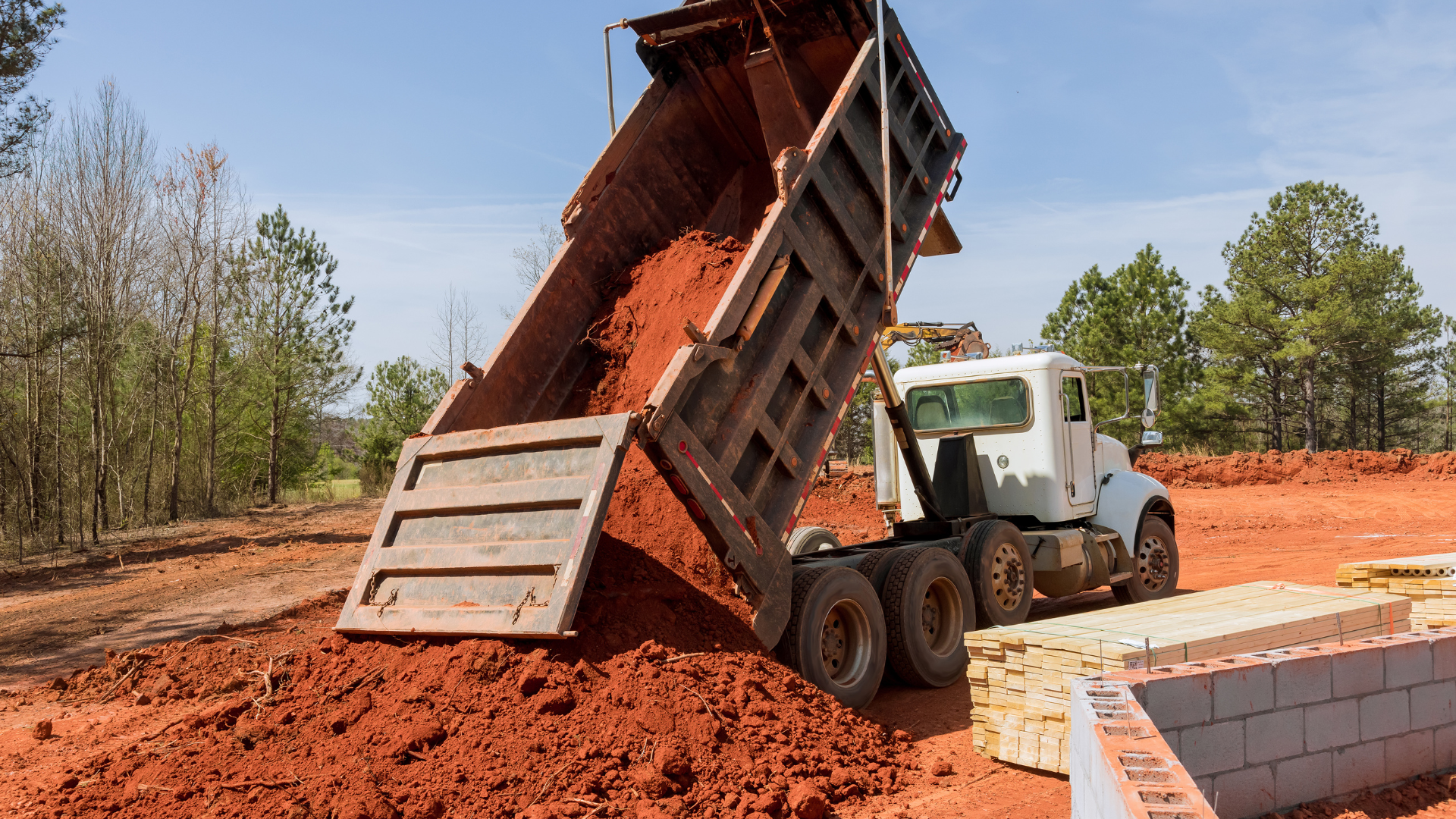 A pile of branches and leaves on the sidewalk next to a trash bag.
